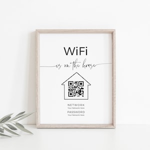Puede incluir: Una impresión enmarcada con un diseño en blanco y negro. La impresión dice "WiFi is on the house" y presenta un icono de casa con un código QR en su interior. El texto "NETWORK" y "PASSWORD" se encuentran debajo del código QR con espacios reservados para el nombre de la red y la contraseña.