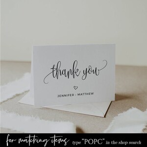 May include: White thank you card with black calligraphy that says "thank you" and a small heart. Below the text is the name "Jennifer Matthew".