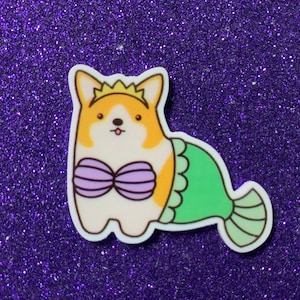 May include: A cartoon sticker of a corgi wearing a purple seashell bra and a green mermaid tail. The corgi is wearing a gold crown and has a light orange and white fur pattern.