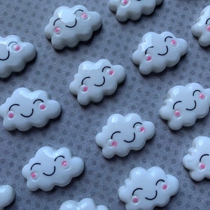May include: A collection of white ceramic cloud shaped ornaments with pink cheeks and black smiling eyes.