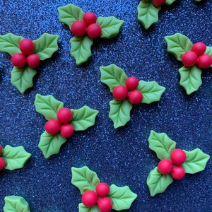 May include: A collection of green holly leaves with red berries. The leaves are arranged in a triangular shape with the berries in the center.