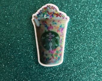 Könnte beinhalten: Nahaufnahme eines Starbucks Frappuccinos mit Streuseln und Schlagsahne. Der Becher ist weiß mit dem Starbucks-Logo und einer grünen Meerjungfrau.