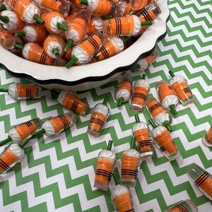 K&ouml;nnte beinhalten: Eine Sch&uuml;ssel gef&uuml;llt mit orangefarbenen und wei&szlig;en Miniatur-Plastikbechern mit gr&uuml;nen Strohhalmen. Die Becher sind auf einer gr&uuml;n-wei&szlig;en Chevron-Oberfl&auml;che verstreut.