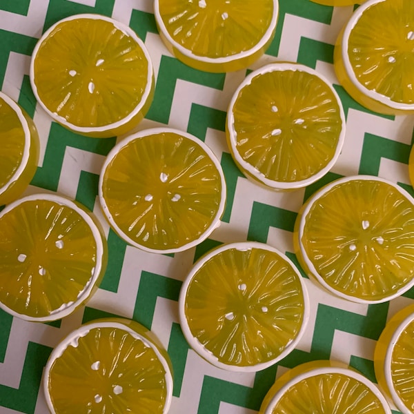 May include: A collection of yellow lemon slices with white edges, arranged on a green and white chevron patterned surface.