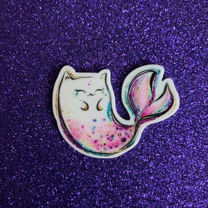 May include: A white cat with pink and purple glitter on its tail, with a mermaid tail, on a purple glitter background.