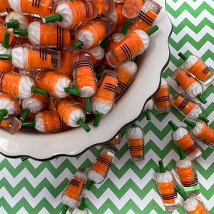 K&ouml;nnte beinhalten: Eine wei&szlig;e Sch&uuml;ssel gef&uuml;llt mit Miniatur-Plastikbechern in Orange und Wei&szlig; mit gr&uuml;nen Strohhalmen. Die Becher sind auf einer gr&uuml;n-wei&szlig;en Chevron-Oberfl&auml;che verstreut.