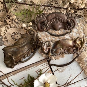 May include: A white ceramic mug with a black handle and the text "But First, Coffee" in a bold, black font. The mug is set against a blurred background, highlighting its clean design.