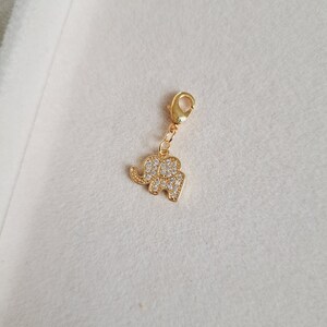 May include: A gold-tone elephant charm with clear rhinestones. The charm has a lobster clasp.