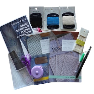 May include: A white ceramic mug with a black handle and the text "But First, Coffee" in a bold, black font. The mug is set against a blurred background, suggesting a cozy setting. The mug appears to be approximately 4 inches tall.