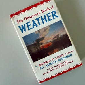 May include: A vintage book titled "The Observer's Book of WEATHER" with a landscape image on the cover. The book has a white cover with red trim and blue text. The book is by Reginald M. Lester and describes all aspects of weather.