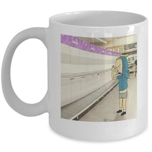May include: A white ceramic coffee mug with a cartoon image of a person in a blue shirt and shorts standing in an empty grocery store aisle. The text "Toilet Paper" is visible on a shelf in the background.