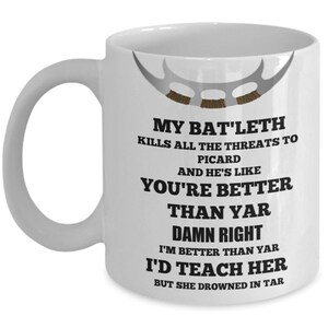 May include: White ceramic coffee mug with a black and white graphic design. The design features a Klingon Bat'leth weapon and text that reads "My Bat'leth kills all the threats to Picard and he's like you're better than yar damn right I'm better than yar I'd teach her but she drowned in tar."