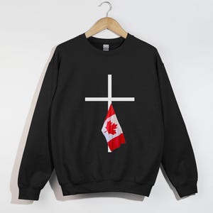 Peut inclure: Sweat-shirt noir avec une croix blanche et un drapeau canadien suspendu au bas de la croix.