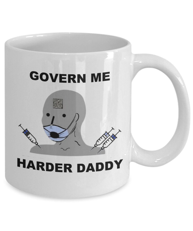 May include: White ceramic mug with a humorous design. The mug features the text "GOVERN ME HARDER DADDY" with a cartoon figure wearing a face mask and syringes. The mug has a curved handle.