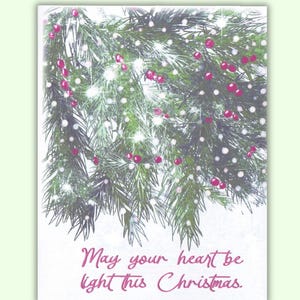 May include: A Christmas greeting card featuring a festive design. The card displays a detailed illustration of a Christmas tree branch adorned with red berries and white lights. The text "May your heart be light this Christmas" is written in a cursive font.