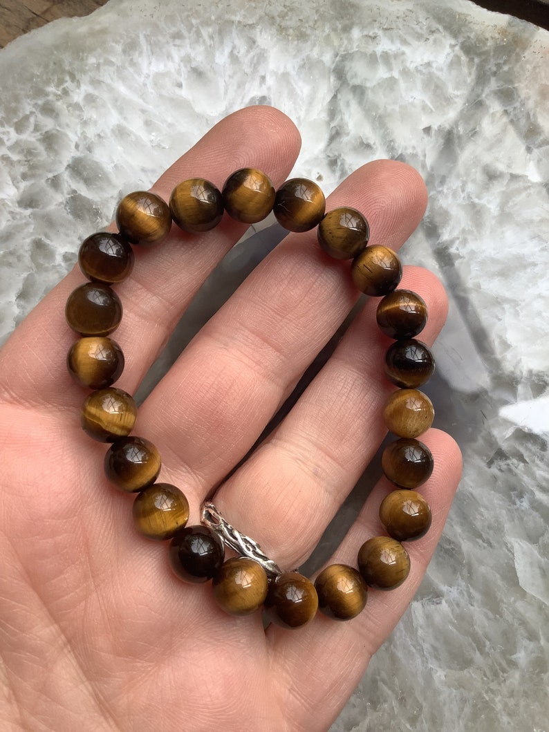 May include: A brown and gold tiger's eye beaded bracelet. The bracelet is made of round beads and is strung on elastic.