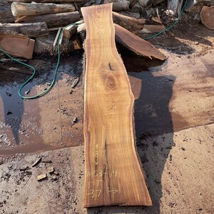 May include: A large, brown wood slab with a natural edge. The slab is approximately 81 inches long and 37 inches wide. The wood has a beautiful grain pattern and is perfect for a variety of woodworking projects.