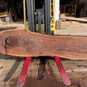 Puede incluir: Una gran losa de madera marr&oacute;n oscura con un nudo. La madera tiene 31 pulgadas de ancho, 119 pulgadas de largo y 3 pulgadas de grosor. La madera est&aacute; etiquetada como "W155-4".