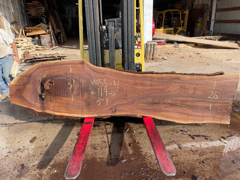 Puede incluir: Una gran losa de madera marr&oacute;n oscura con un nudo. La madera tiene 31 pulgadas de ancho, 119 pulgadas de largo y 3 pulgadas de grosor. La madera est&aacute; etiquetada como "W155-4".