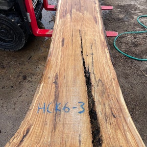 K&ouml;nnte beinhalten: Eine gro&szlig;e, hellbraune Holzplatte mit einer nat&uuml;rlichen Kante. Die Platte hat einen dunkelbraunen Riss, der durch die Mitte verl&auml;uft. Die Platte ist mit blauer Schrift gekennzeichnet, die "HCK6-3" lautet.