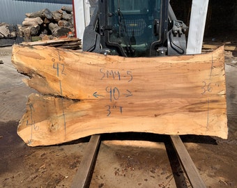 May include: A large, light brown wood slab with a natural edge. The slab is 42 inches wide, 90 inches long, and 3 inches thick. The wood has a natural grain pattern and is marked with measurements in inches.