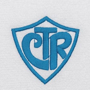 May include: White bath towel with a blue embroidered shield design. The shield contains the letters CTR in a stylized font. The towel has a textured surface and a ribbed border.