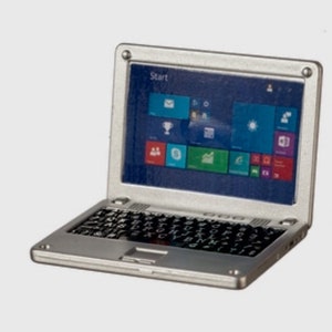 May include: A silver laptop computer with a black keyboard and a screen displaying a Windows desktop with various icons. The screen also displays the word "Start" in the top left corner.