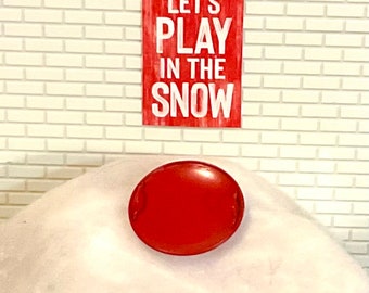 Trineo de metal redondo rojo en miniatura de casa de muñecas o letrero "Juguemos en la nieve". Escala 1:12