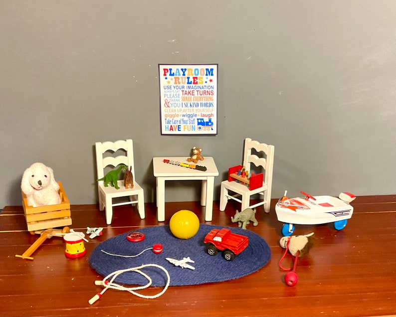 May include: A white wooden table and chairs with a variety of toys, including a stuffed dog, a dinosaur, a toy car, a jet ski, a yellow ball, and a red toy truck. The table has a sign that reads "Playroom Rules: Use your imagination, please take turns, & you use kind words, clean up after yourself, giggle, wiggle, laugh, take care of your stuff, have fun."