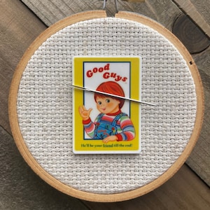 May include: A yellow and white card with a picture of a boy with red hair and a striped shirt. The card says "Good Guys" and "He'll be your friend till the end!" The card is in a wooden embroidery hoop.