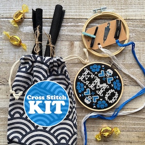 May include: Cross stitch kit with a black and white patterned fabric bag, a blue and white embroidery hoop with the text "Hello" in blue, and a blue and white embroidery floss.