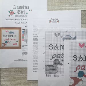 Puede incluir: Instrucciones de punto de cruz para un patr&oacute;n de muestra, "Sam" y "Pat" con un pato y un coraz&oacute;n. El patr&oacute;n incluye colores de hilo DMC y una cuadr&iacute;cula para bordar.