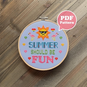 May include: A cross-stitch embroidery hoop with a light blue background. The design features a sun wearing sunglasses, flamingos, and the words "SUMMER SHOULD BE FUN" in various colors. The text "PDF Pattern" is in a pink speech bubble.