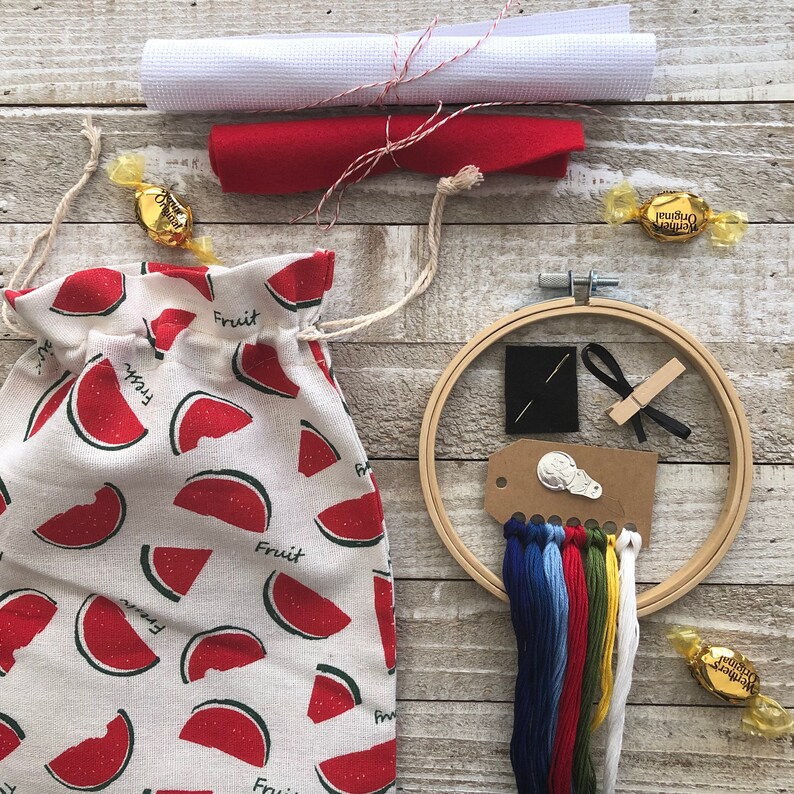 Puede incluir: Una bolsa de tela con estampado de sand&iacute;a con cierre de cord&oacute;n, un aro de bordado de madera con hilo, una aguja y un trozo de tela. El aro de bordado tiene un di&aacute;metro de 25 cm.