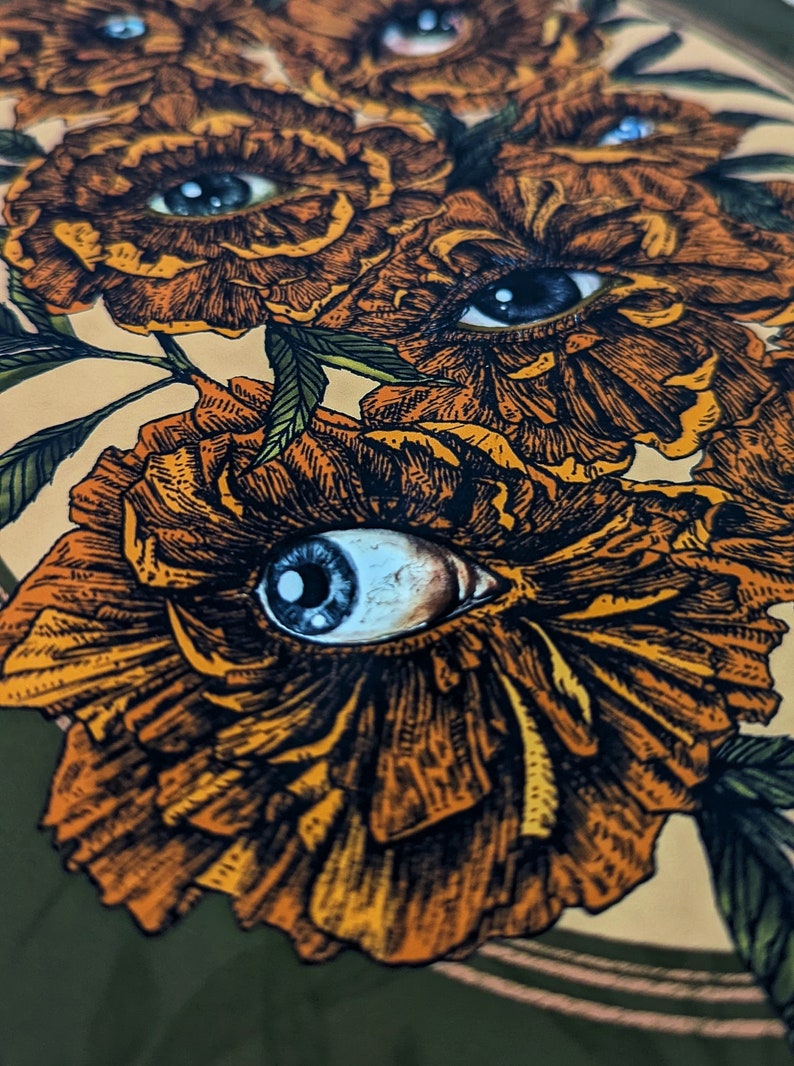 Photo of an art print showing hand drawn golden flowers with photorealistic eyes at the centre of each.