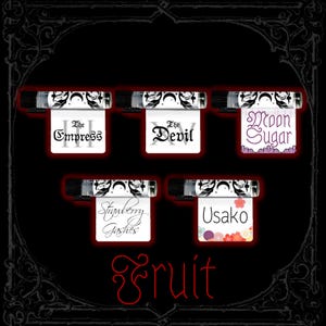 May include: Five small glass vials with black caps, each featuring a white label with black moon and leaf motifs. Labels display the text: The Empress, The Devil, Moon Sugar, Strawberry Gashes, and Usako. The word Fruit is written in red below.