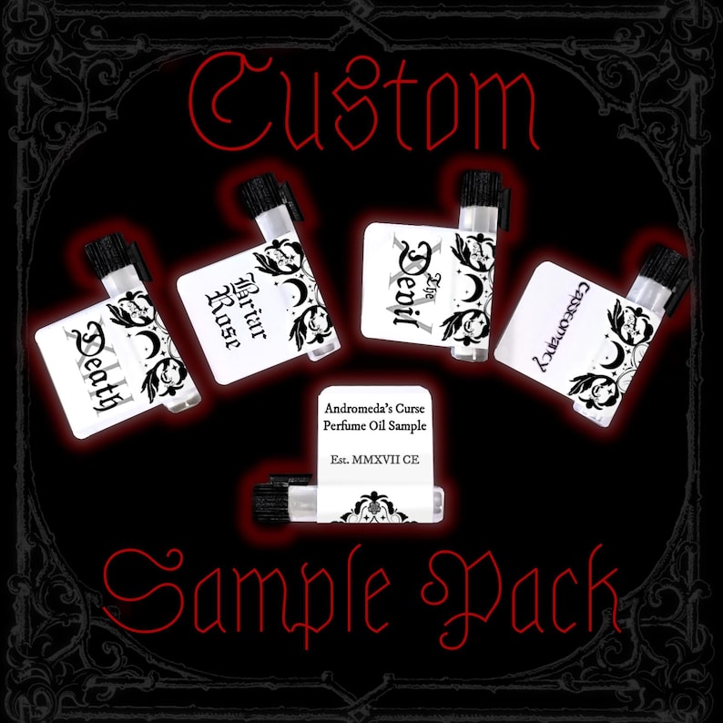 May include: Five small clear glass perfume oil sample vials with black caps, each featuring a white label with black text and decorative motifs. Labels read Death, Briar Rose, The Devil, Cartomancy, and Andromeda's Curse Perfume Oil Sample Est. MMXVII CE.