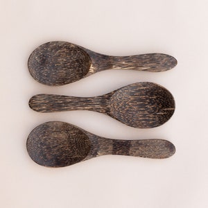 Puede incluir: Tres cucharas pequeñas de madera con veta de madera marrón oscuro y negro. Las cucharas están dispuestas en fila, con los mangos apuntando hacia la derecha.