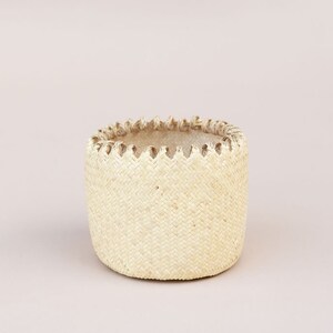 May include: A white woven basket with a decorative trim around the top.