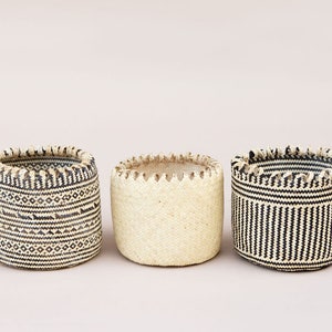 May include: Three woven baskets with black and white patterns. The baskets are made of natural materials and have a rustic look.