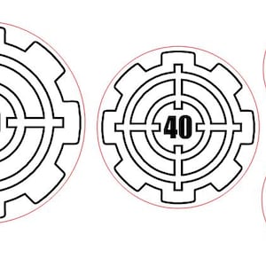 Op de afbeelding: Vier zwarte en witte ronde stickers met een tandwielontwerp. De stickers hebben verschillende ontwerpen, waaronder een doelwit met het nummer 50, een doelwit met het nummer 40, een krat en een vlag met een zwaard.