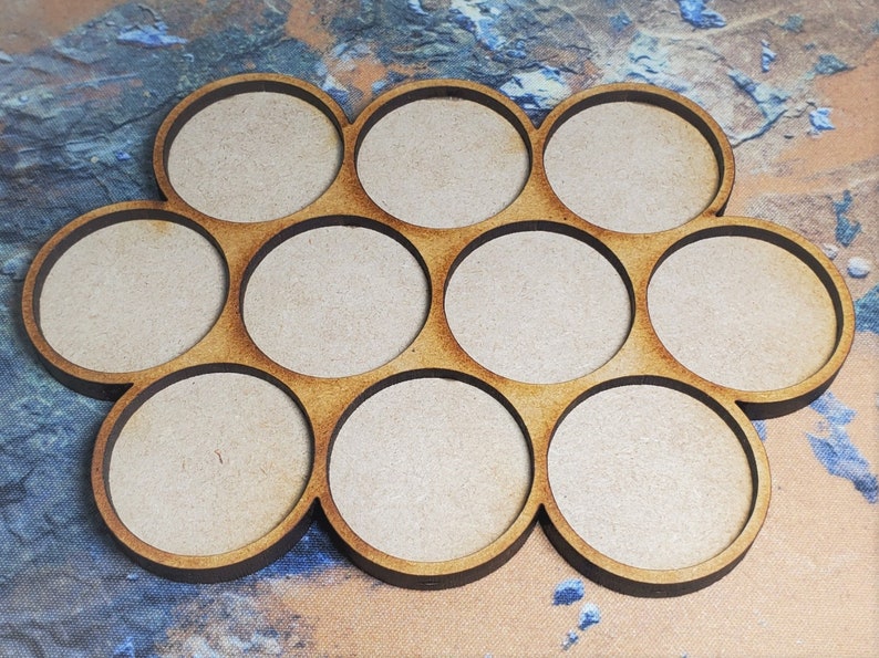 Peut inclure: Un plateau en bois avec dix compartiments circulaires, parfait pour organiser de petits objets. Le plateau est en bois naturel et a un aspect rustique et artisanal.