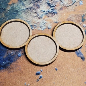 May include: Three unfinished wooden circles, each with a raised edge, are arranged in a semi-circle pattern. The circles are all the same size and are made of a light brown wood.