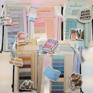 May include: A collection of reading list kits with stickers, pens, and sticky notes. The kits include beige canvas pouches, reading lists, and stickers with phrases like "Read More Books" and "Read a Damn Book." The color palette includes pastel pinks, blues, and beige.