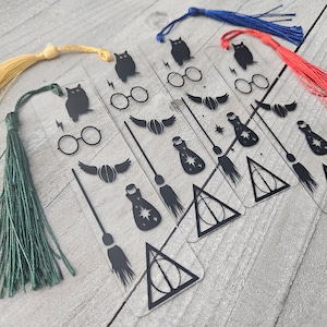 May include: Five clear bookmarks with black designs. The designs include an owl, a cat, a broom, a potion bottle, and the Deathly Hallows symbol. Each bookmark has a tassel.