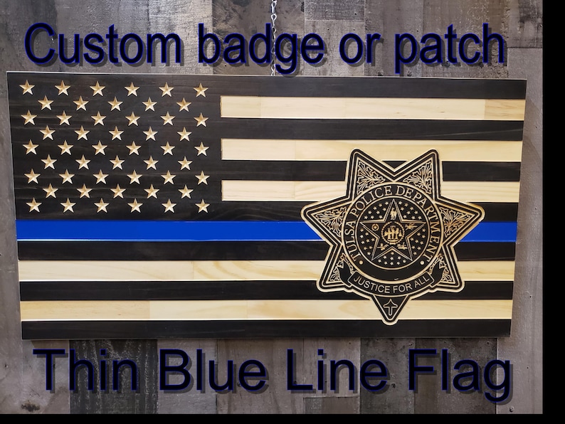 K&ouml;nnte beinhalten: D&uuml;nne blaue Linie Flagge aus Holz mit blauem Streifen und geschnitzten Sternen. Mit einem Abzeichen der Polizei von Tulsa. Der Text lautet "Custom badge or patch" und "Thin Blue Line Flag".