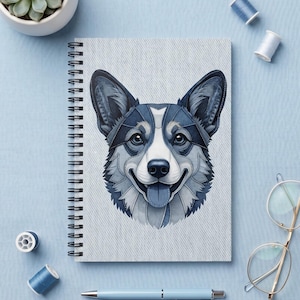 May include: A spiral-bound notebook featuring a graphic illustration of a Corgi dog face composed of various shades of blue denim fabric textures. The dog has large pointed ears, a white muzzle, and a blue tongue, set against a light blue background.