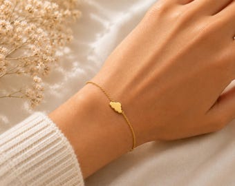May include: A delicate gold-tone chain bracelet featuring a small, centered cloud-shaped charm. The bracelet is constructed with a fine link chain and a polished metal finish, creating a simple and understated piece of jewelry for the wrist.