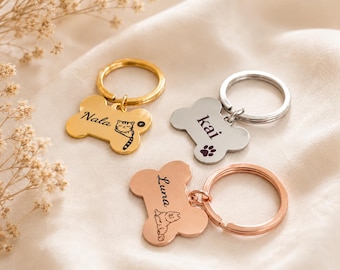 May include: Three bone-shaped metal keychains in gold, silver, and rose gold tones. Each keychain features a split ring and is engraved with a name and a small animal illustration. The gold tag says Nala, the silver tag says Kai, and the rose gold tag says Luna.