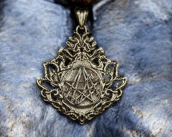 May include: A gold-toned pendant with a five-pointed star design, surrounded by a decorative floral pattern.